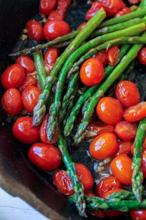 asparagus and cherry tomatoes in a cast iron pan. 