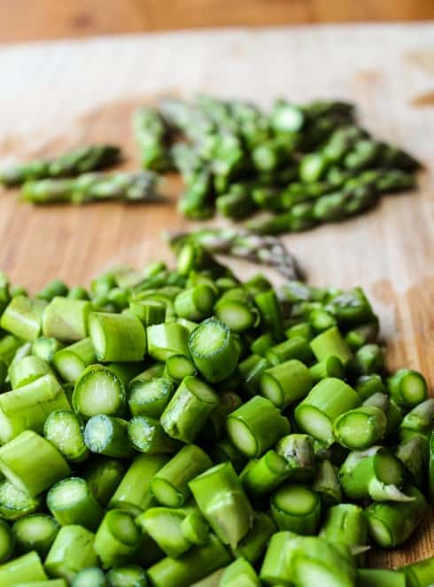 cut up asparagus on a wooden cutting board.