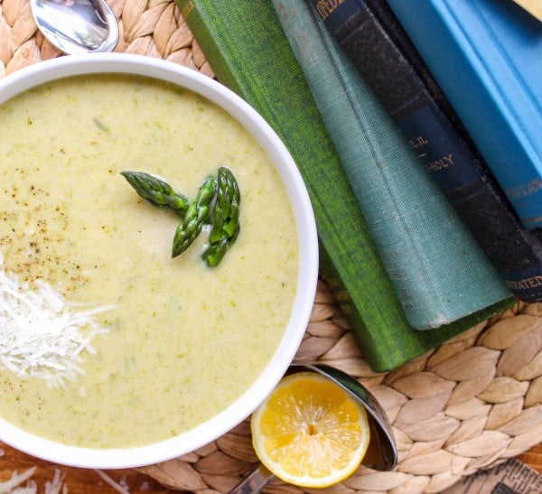 a bowl of creamy asparagus soup with books next to it.