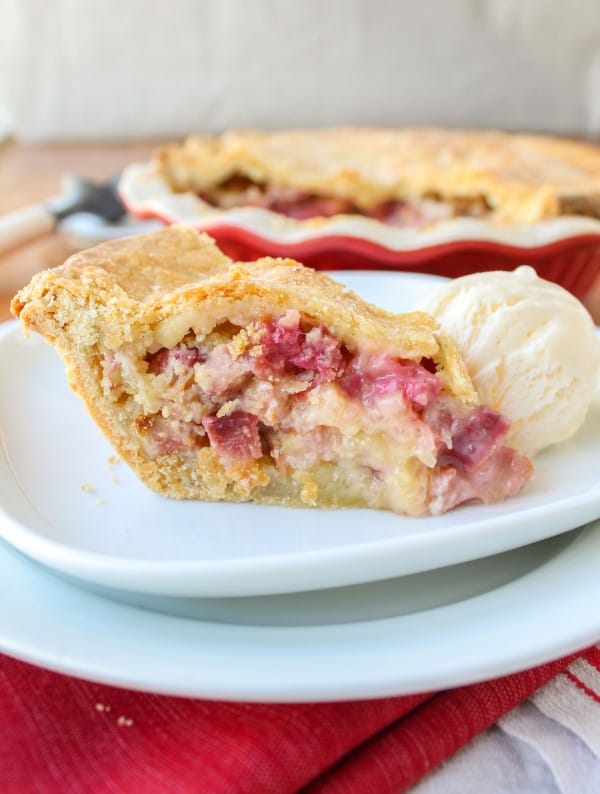 a slice of rhubarb custard pie on a plate with ice cream. 