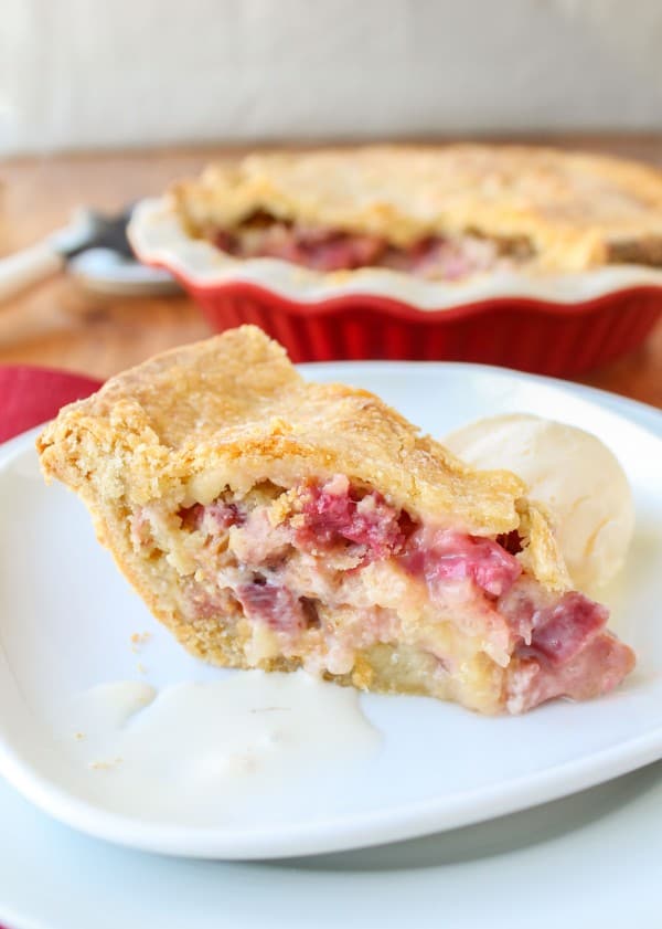 a slice of rhubarb custard pie on a plate with vanilla ice cream. 