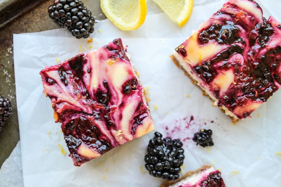 blackberry lemon cheesecake bars on parchment paper.