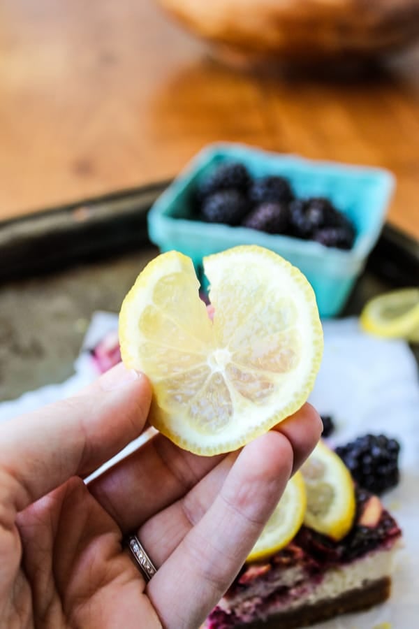 a hand holding a thinly sliced lemon with a slit in it. 