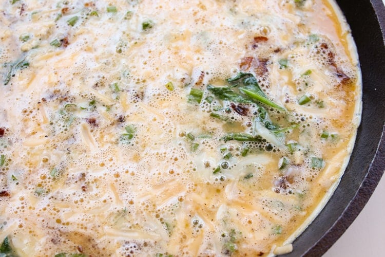 Uncooked frittata in cast iron skillet.
