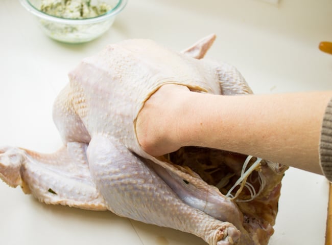 Stuffing butter under the skin of a whole turkey.