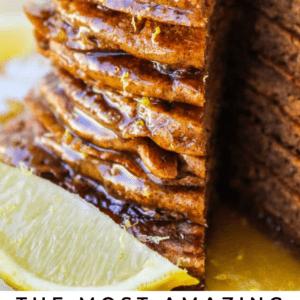 A tall stack of gingerbread pancakes topped with butter and syrup, garnished with lemon zest and fresh lemon slices on the side. Text at the bottom reads: The Most Amazing Gingerbread Pancakes.