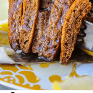 A close-up of a fork cutting into fluffy gingerbread pancakes, drizzled with lemon buttermilk syrup and topped with melted butter. Text below reads: Gingerbread Pancakes with Lemon Buttermilk Syrup.