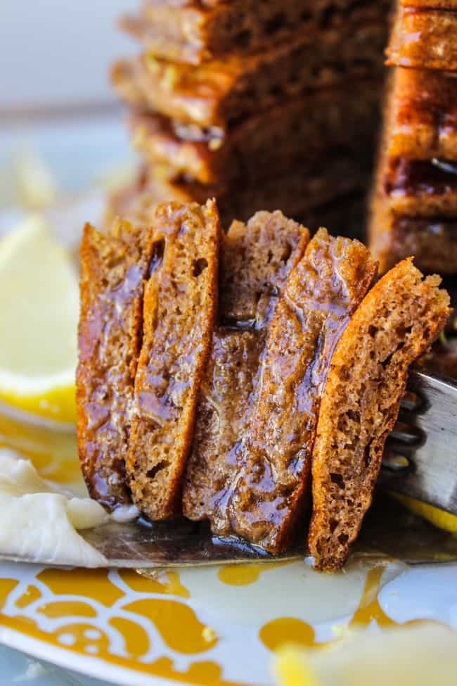 stacked bites of gingerbread pancakes on a fork, drizzled in lemon syrup.