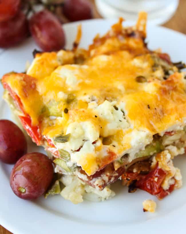 egg, bacon, and asparagus casserole on a plate with grapes.