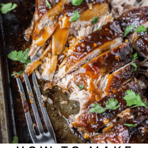 A glazed pork tenderloin sliced on a wooden board, topped with chopped cilantro and served with a lime wedge. A fork rests nearby. Text reads: Asian Style Pork Tenderloin. The Food Charlatan.