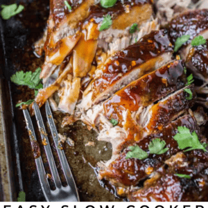 Sliced pork tenderloin with a glossy sauce, garnished with cilantro, sits on a pan with a fork and a lime wedge. Text reads: Slow Cooker Asian Style Pork Tenderloin with bold flavors - The Food Charlatan.