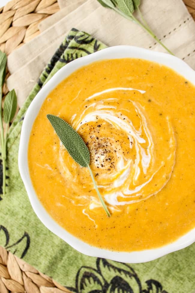 a bowl of butternut squash soup with cream and fresh sage. 