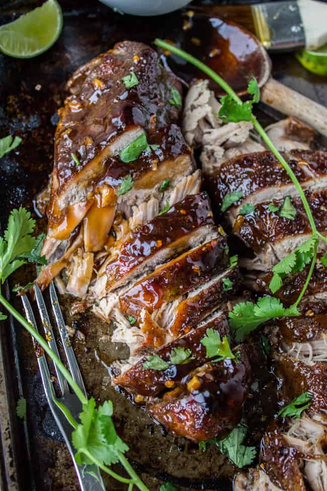 sliced pork tenderloin with sticky sweet glaze, fresh cilantro, and lime wedges.