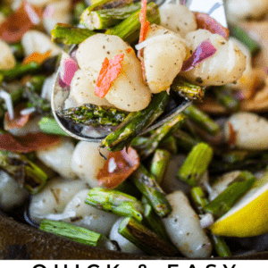 A skillet filled with gnocchi, asparagus, and prosciutto, garnished with lemon wedges. Overlay text reads: “Quick & Easy Brown Butter Gnocchi with Asparagus & Prosciutto. The Food Charlatan.”