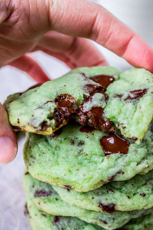 green chocolate chip cookies stacked with hand holding top one, mint flavored