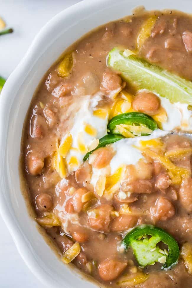 traditional tejano pinto beans (slow cooker Mexican beans) garnished with lime, sour cream, jalapenos, and cheddar.