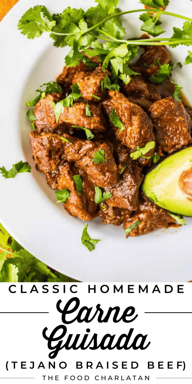 a white plate piled high with carne guisada, topped with cilantro and avocado.