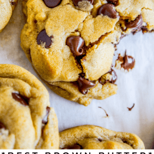a chocolate chip cookie with a bite taken out of it on parchment paper and other cookies nearby.