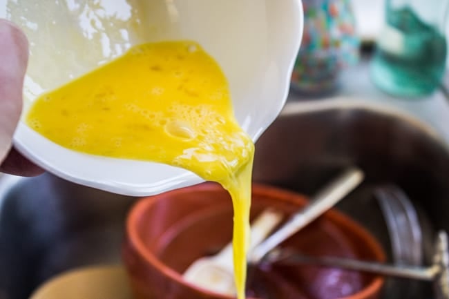 Beaten eggs being poured from a bowl.