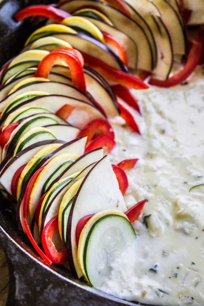 layering sliced vegetables to make ratatouille with sauce.