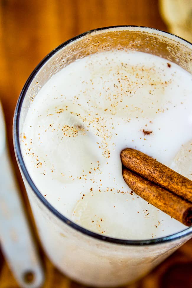 a tall glass of horchata with ice and a cinnamon stick.