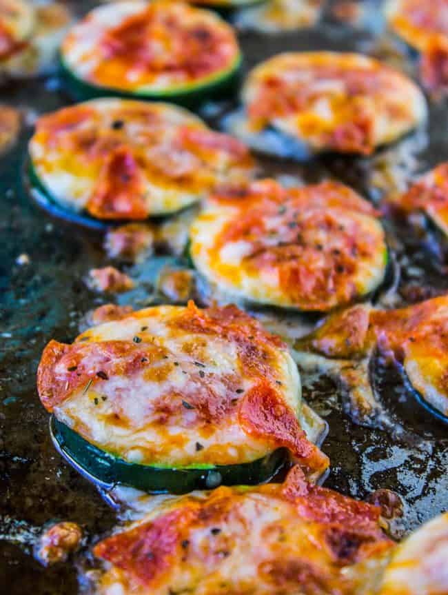sliced zucchini roasted on a pan with pizza toppings.