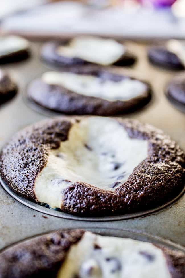 chocolate cupcakes with cream cheese filling baking in a muffin tin. 