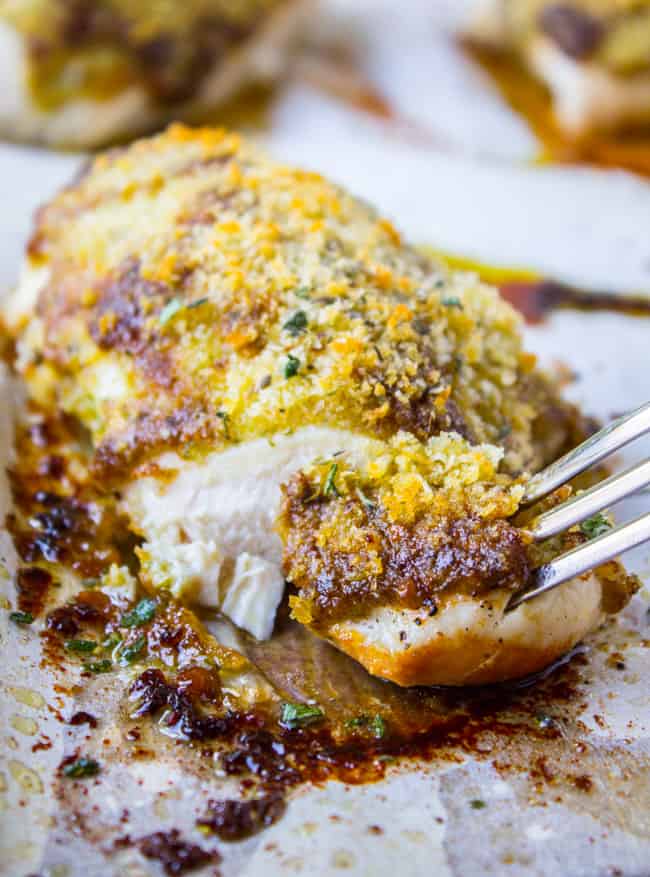 a fork taking a bite of baked pesto chicken. 