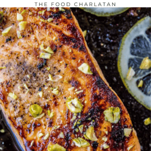 Pan-seared salmon with a maple glaze and chopped pistachios, served with lemon slices.