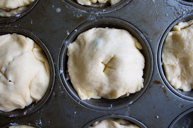 Uncooked mini chicken pot pies in a muffin tin with slits for venting steam.