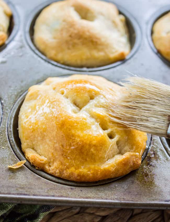 Golden brown mini chicken pot pie with butter brushed on by a pastry brush. 