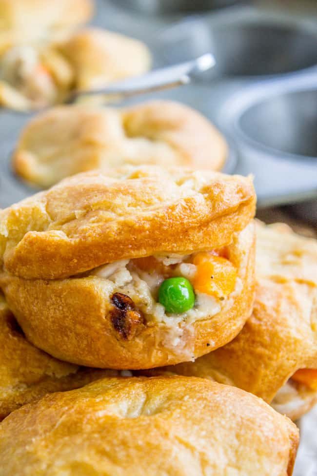 Individual mini chicken pot pies with crescent rolls stacked by a muffin tin. 