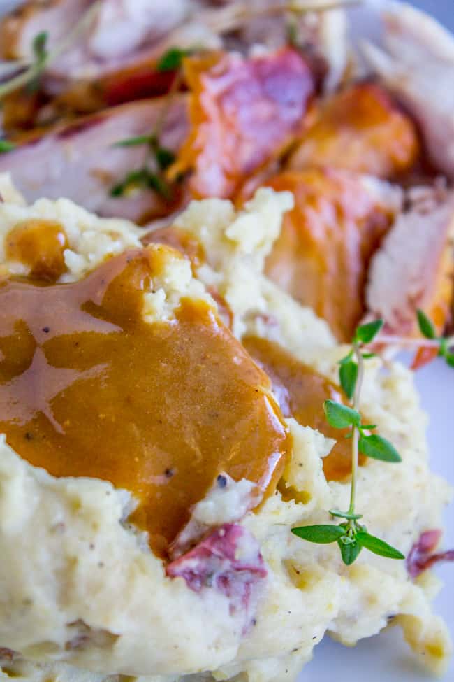 homemade turkey gravy on red mashed potatoes with fresh thyme and roast turkey.