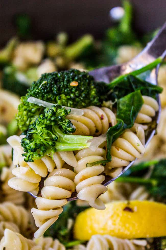 closeup of pasta with broccoli and spinach on a spoon.