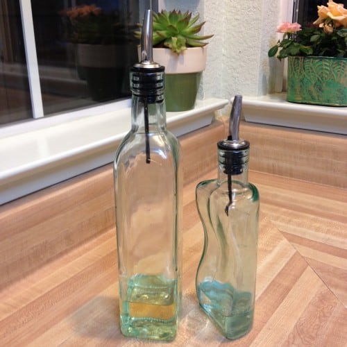 A partially-full glass bottle next to a partially full smaller glass bottle