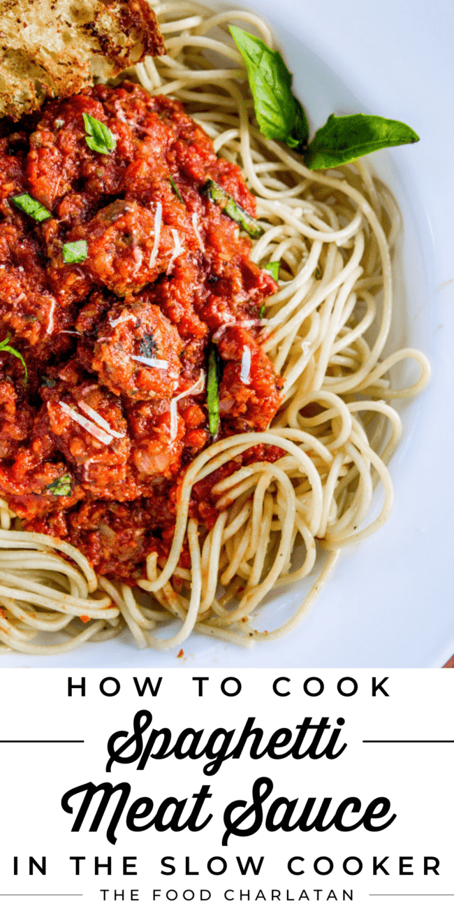 slow cooker spaghetti meat sauce served over spaghetti noodles with fresh basil.