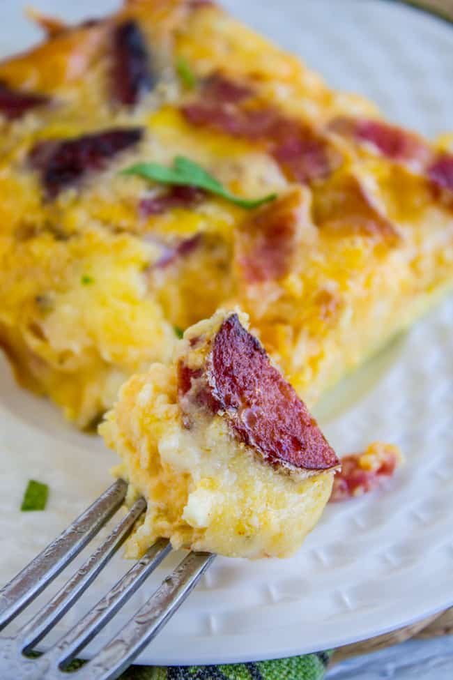 slice of egg and cheese casserole on a white plate with fork lifting one bite