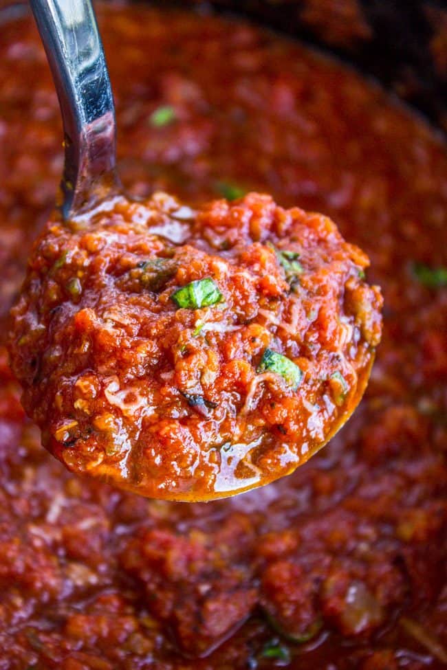 Slow cooker spaghetti sauce with Italian sausage being lifted with a ladle.