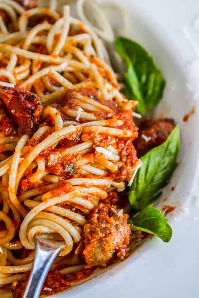 Spaghetti sauce served over pasta with fresh basil, twirled on a fork.