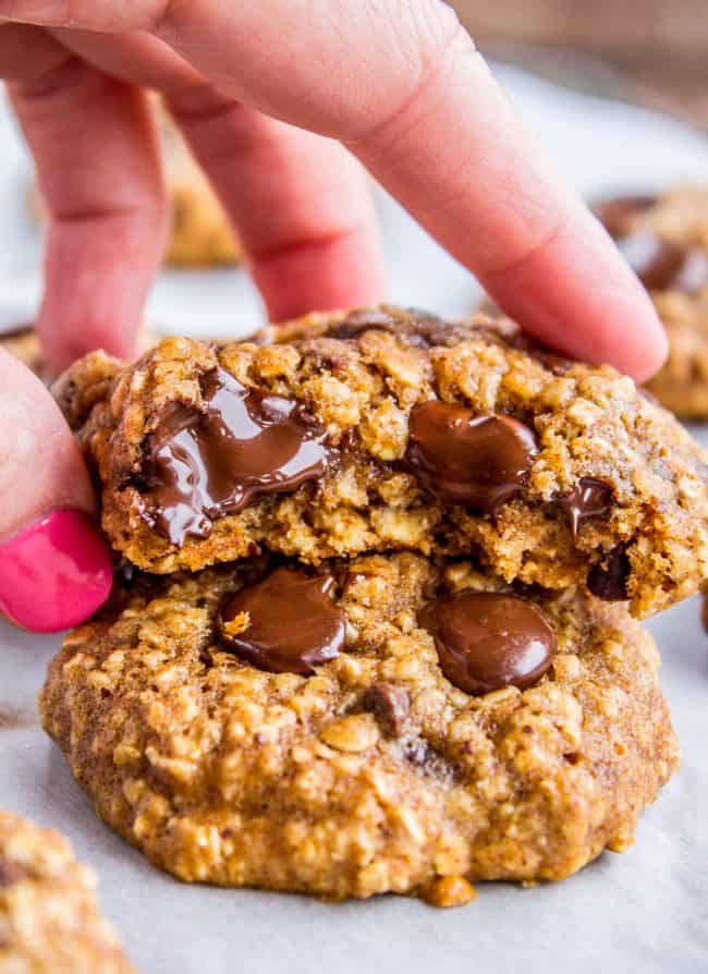 oatmeal chocolate chip cookies with bite taken out and hand lifting it