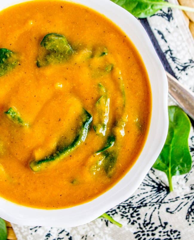 creamy golden cauliflower soup in a white bowl.