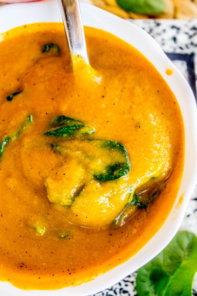 creamy cauliflower soup in a white bowl with a spoon. 