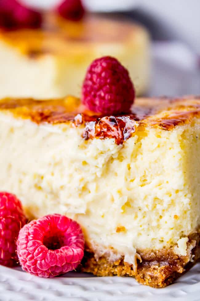 Crème Brûlée Cheesecake shot from the side with fresh raspberries. 