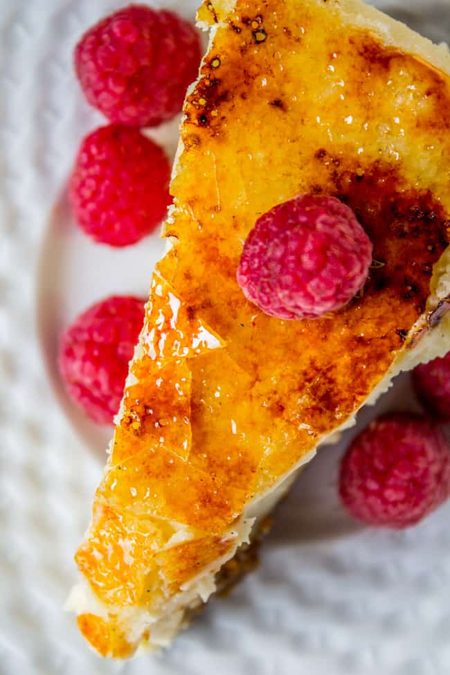 a slice of Crème Brûlée Cheesecake shot from above with fresh raspberries.