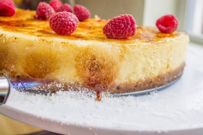 torching the edges of a cheesecake topped with raspberries. 