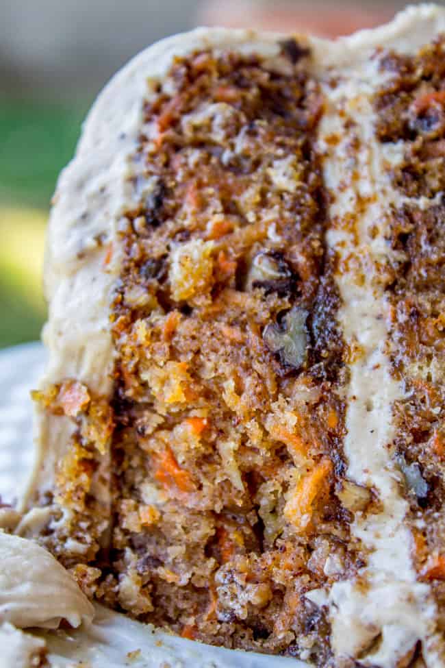 a close up shot of a slice of carrot cake with cream cheese maple pecan frosting. 