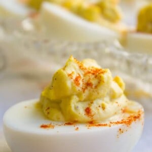 deviled egg with paprika sprinkled on top and more eggs in the background.