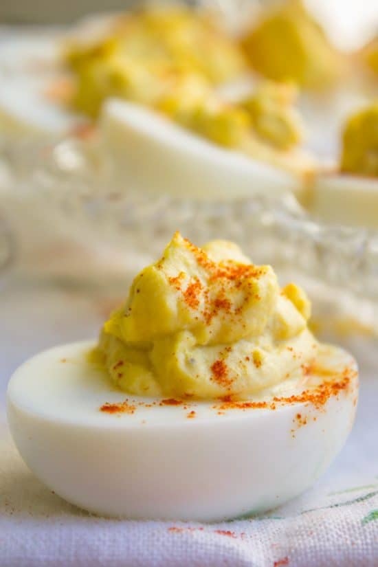 deviled egg with paprika sprinkled on top and more eggs in the background.