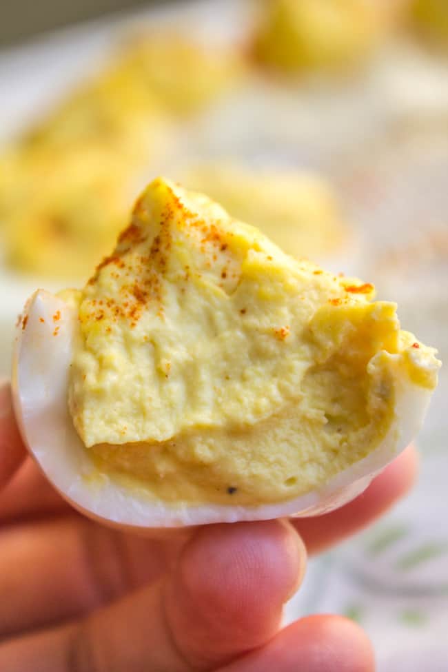 deviled egg sprinkled with paprika with a bite taken out of it.
