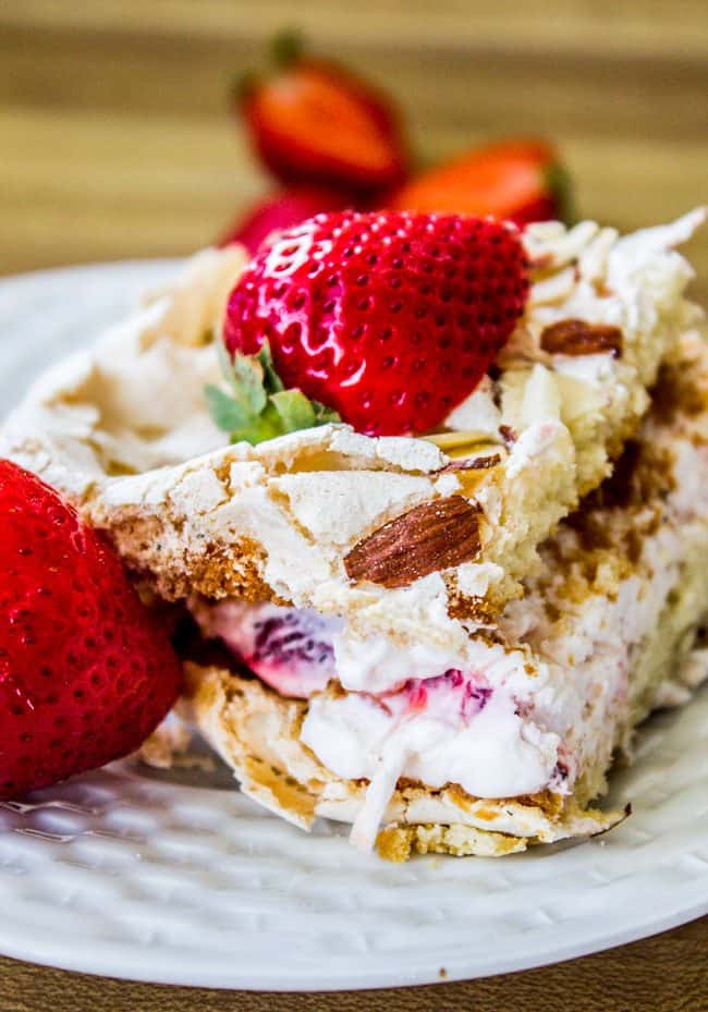 Slice of strawberry merinque cake with creamy center and almonds.